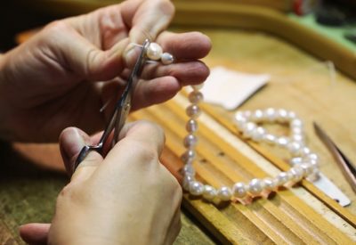 Woman hands threading a pearl necklace
